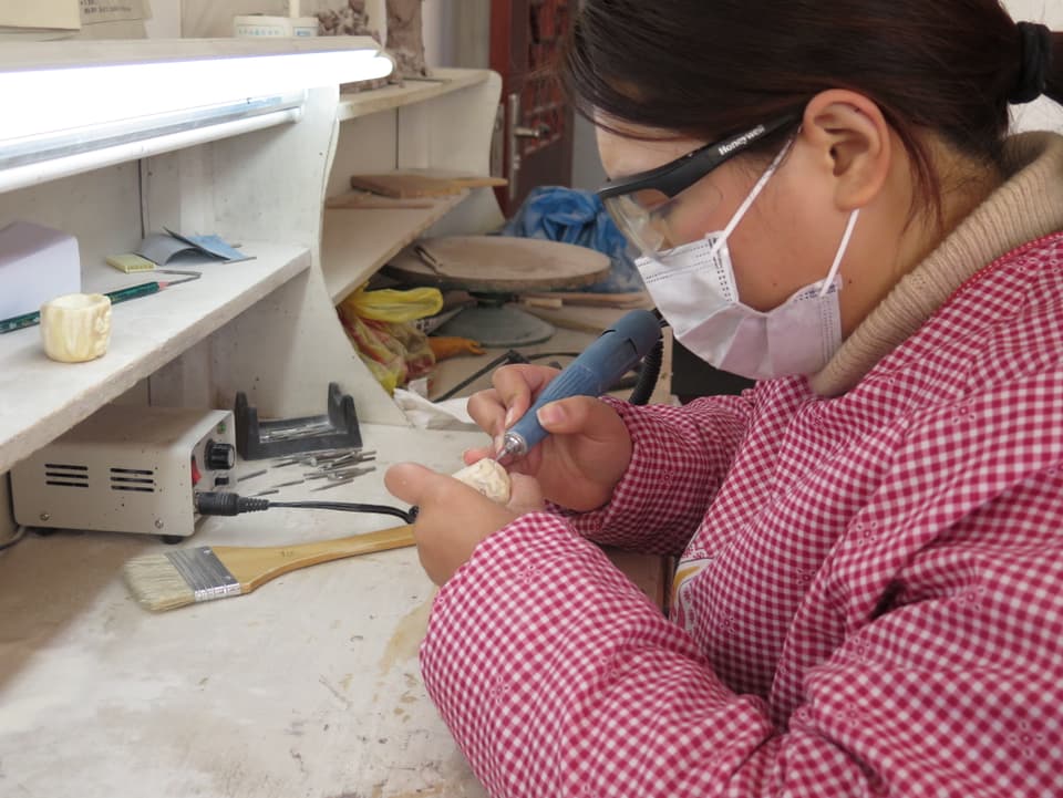 Elfenbeinschnitzerin bei der Arbeit mit einem Zahnborer.