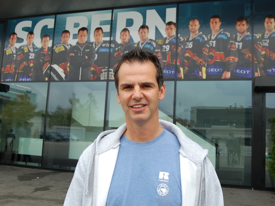 SCB-Sportchef Sven Leuenberger vor dem Berner Eisstadion. Im Hintergrund die grossen Bilder der SCB-Mannschaft.