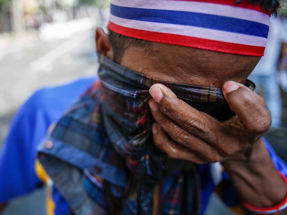 Ein Regierungsgegner in Bangkok verdeckt sein Gesicht mit einem nassen Lappen. (reuters)