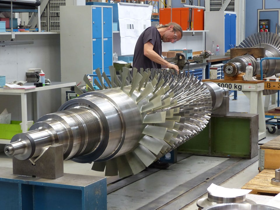 Ein Arbeiter arbeitet an einer metallischen Turbine.