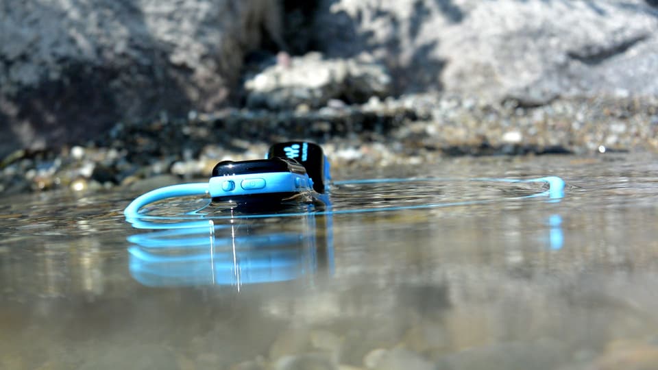Ein Kopfhörer in Türkis, im Wasser.