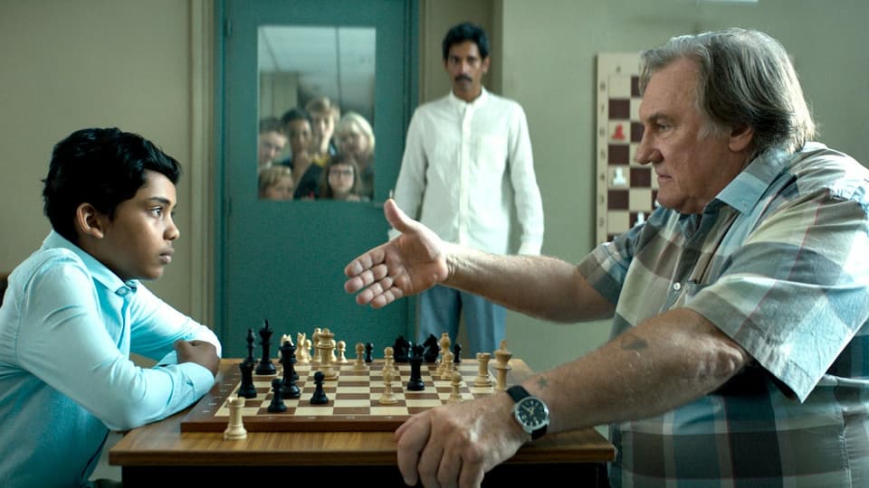 Ein junge aus Bangladesh und ein älterer Mann spielen gegeneinander Schach. 
