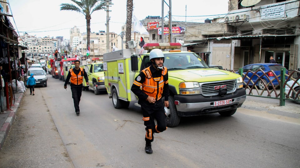 Uniformeirte und Rettungsfahrzeuge in einer Strasse Gazas.