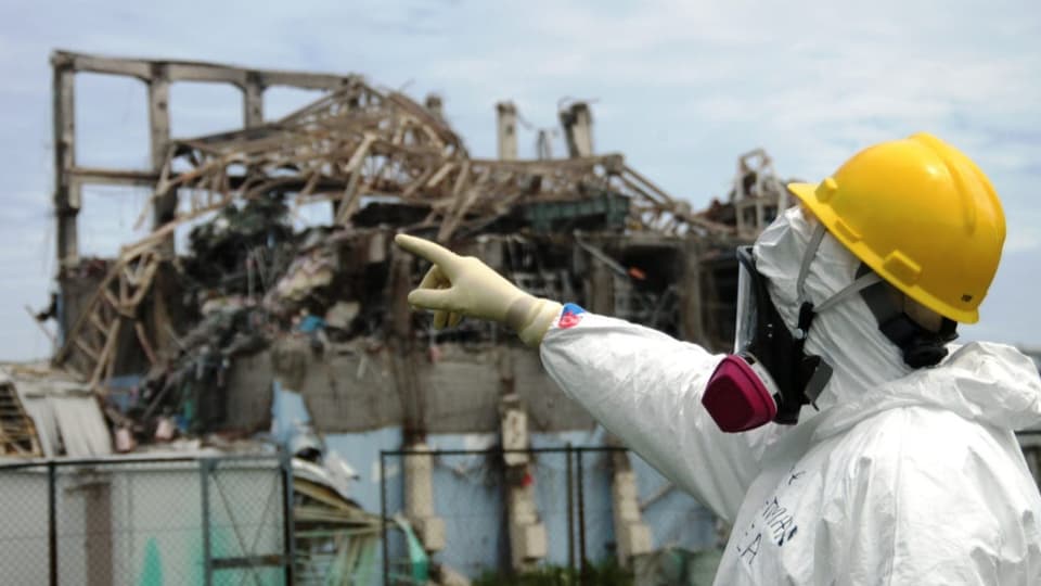Mann in Schutzanzug vor der Atomruine Fukushima