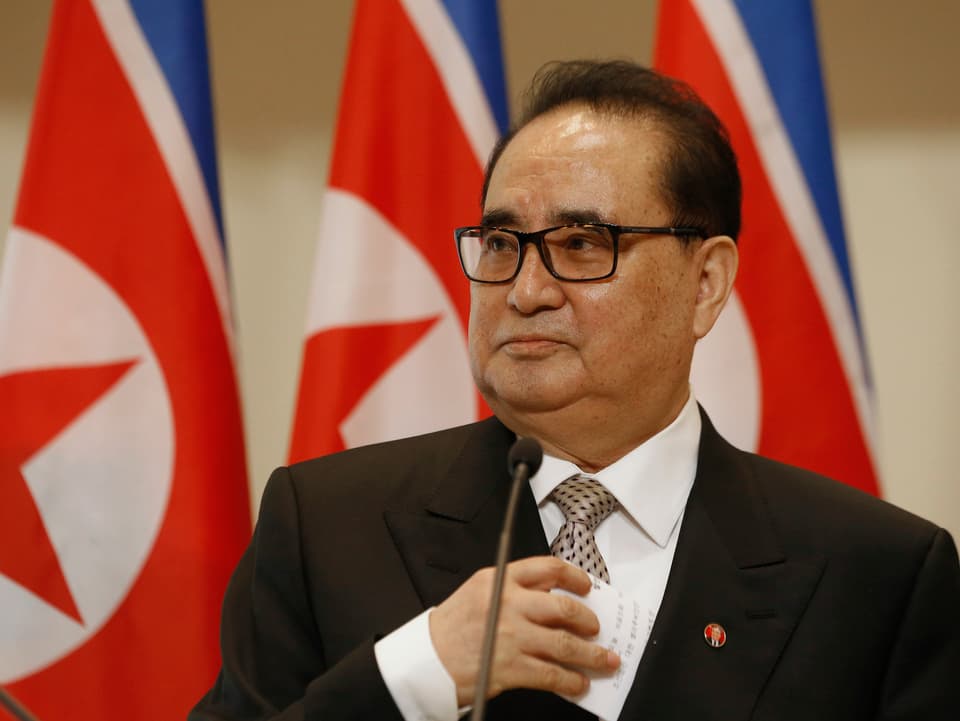 Aussenminister Ri Su Yong vor drei nordkoreanischen Flaggen.