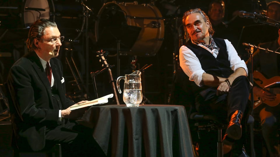 Martin Suter und Stephan Eicher sitzen gemeinsam auf einer Bühne.