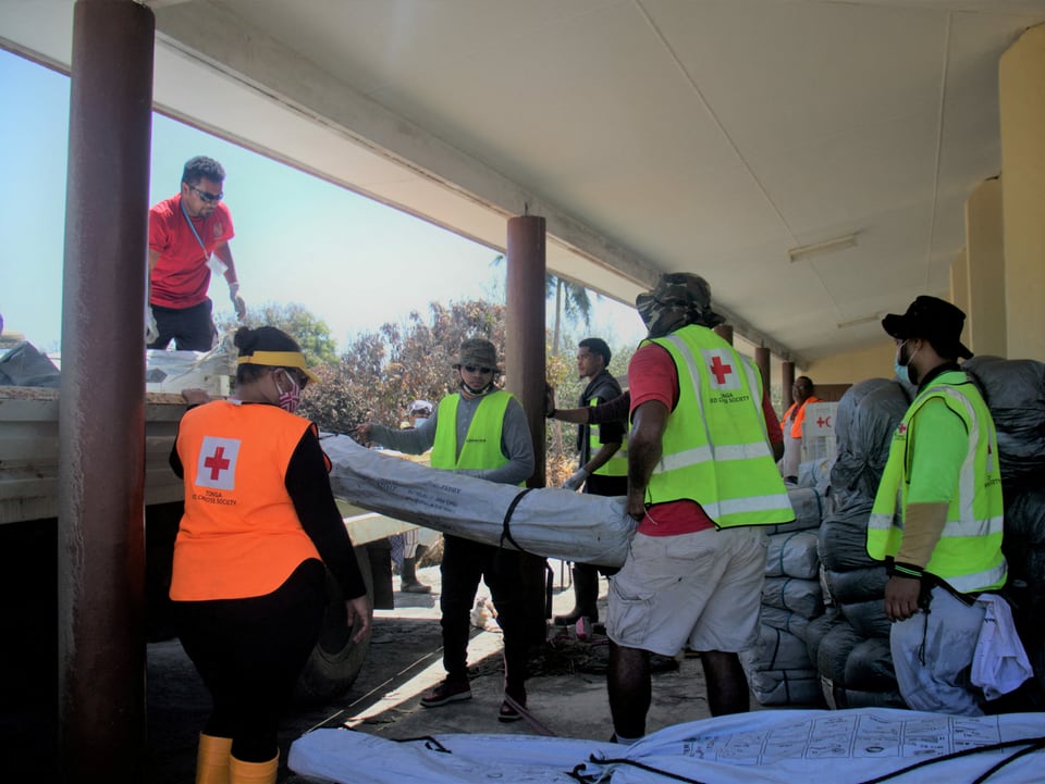 Mitarbeiter des roten Kreuzes verladen Hilfsgüter.