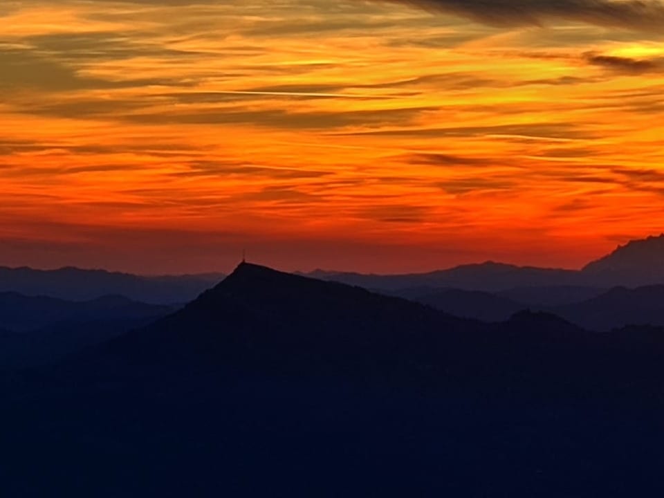Sonnenuntergang über Berglandschaft mit leuchtend orangefarbenem Himmel