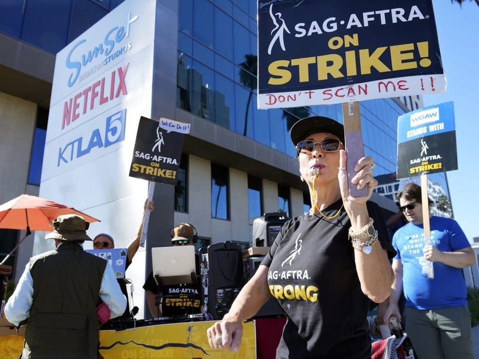 Eine Frau mit einer Trillerpfeife und einem Streikplakat.