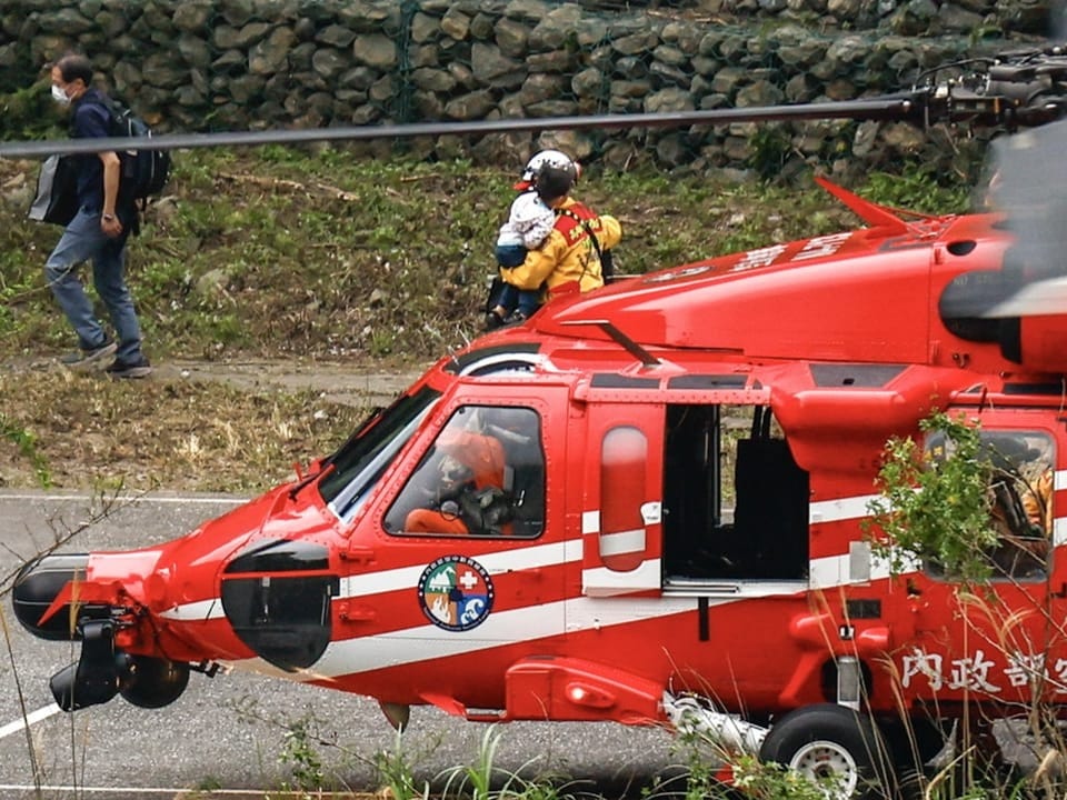 Rettungskräfte bringen eine Familie aus dem Helikopter auf den Parkplatz