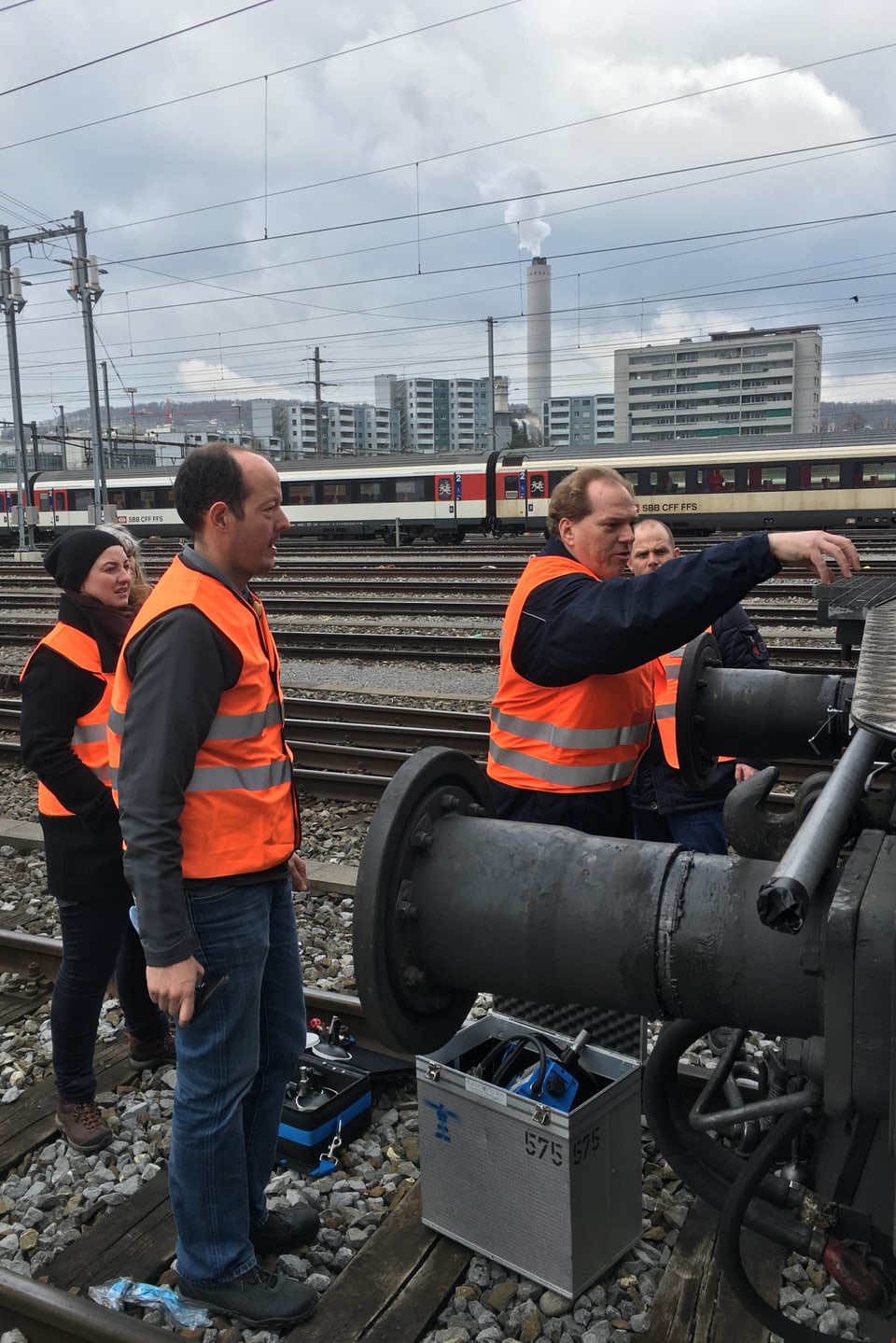 Vier Personen, einer davon montiert eine Gopro an der Vorderseite einer Lok.