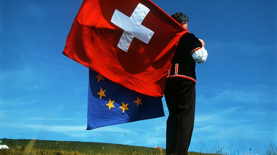 Ein Fahnenschwinger hält die Schweizer und die EU-Fahne.