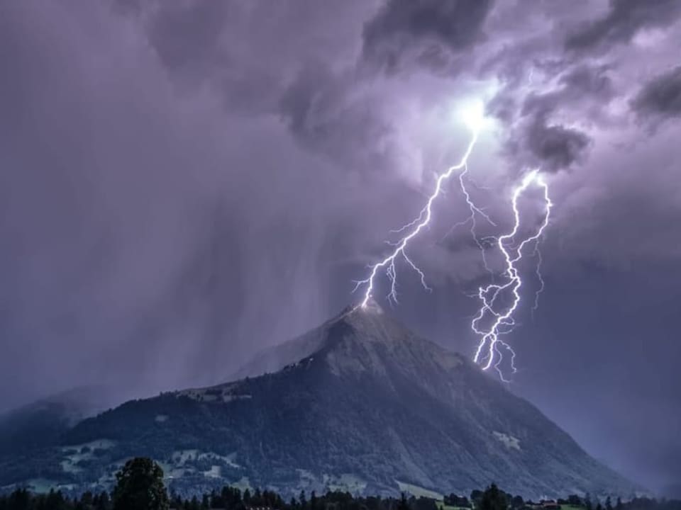 Blitzeinschläge an einem Berg mit dunklen Wolken