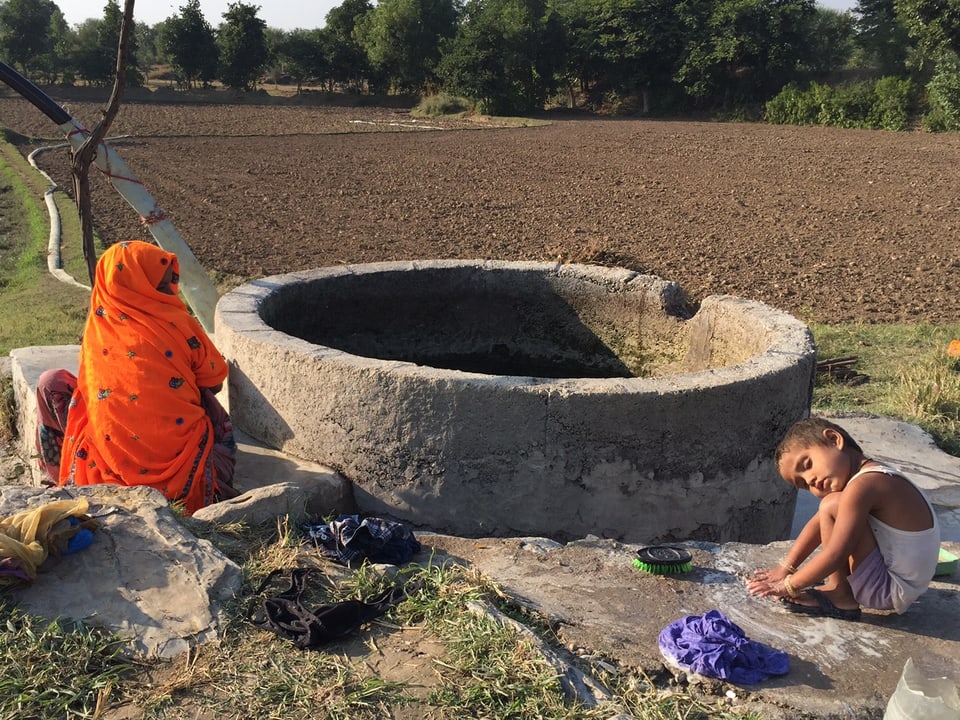 EIn Brunnen in Gopalpura, davor sitzen eine Frau und ein Kind