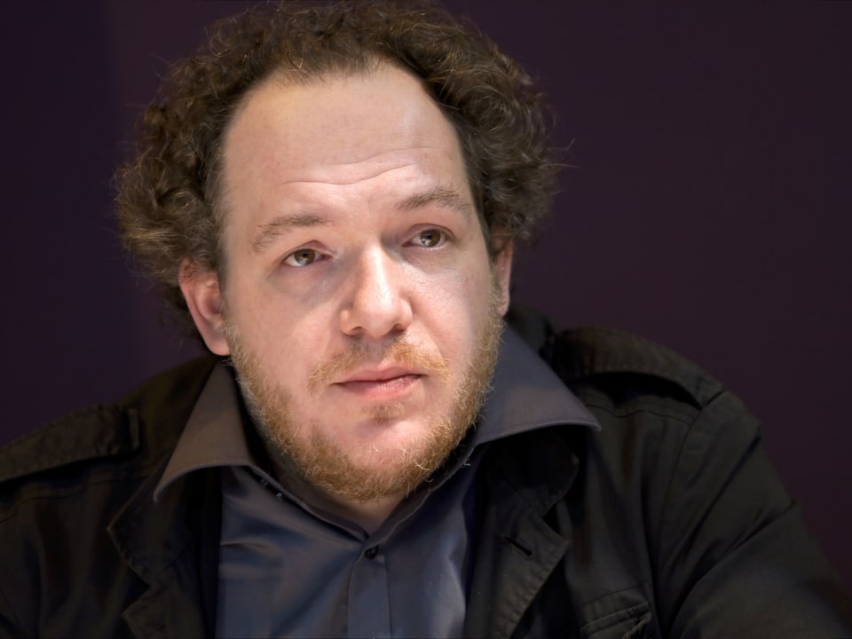 Porträtbild von Mathias Énard, er trägt ein graues dunkelgraues Hemd und ein schwazes Sacko.