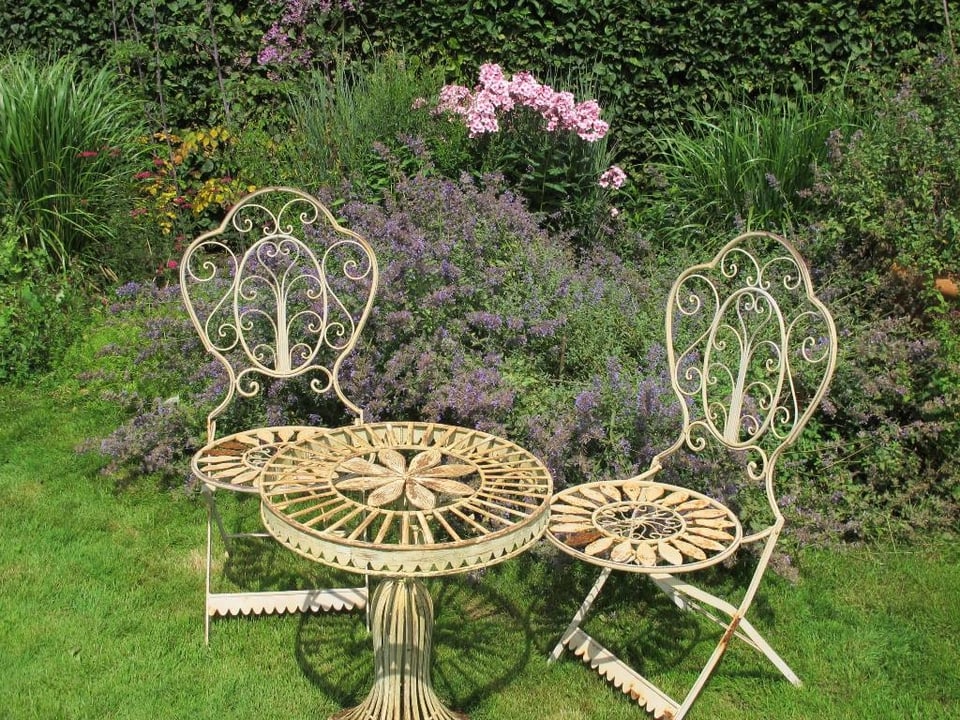 Zwei romantisch designte Stühle in einem Garten.