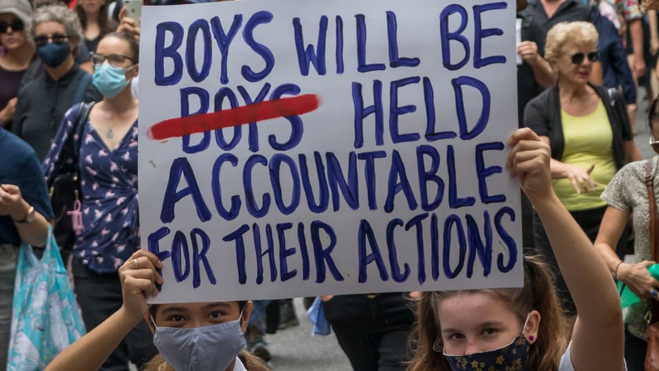 Zwei Mädchen demonstrieren mit einem Transparent auf dem steht: «Boys will be Held Accountable for their actions»