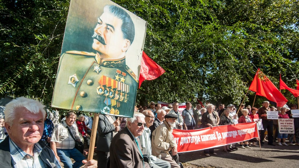 Demonstranten halten ein Plakat mit Stalins Konterfei in die Luft.