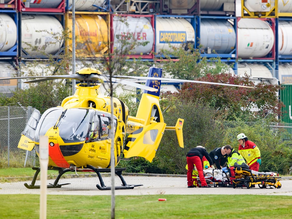 Hubschrauber am Boden, daneben versorgen Sanitäter einen Verletzten.