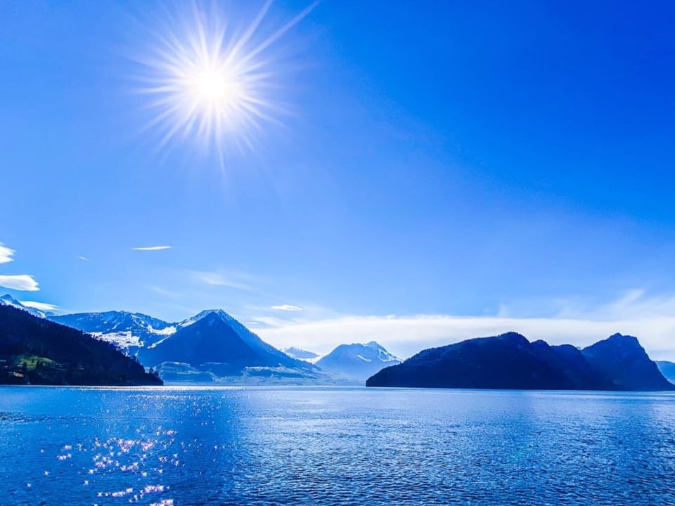 Blick auf einen See und Berglandschaft mit blauem Himmel. Das ganze Foto in Blautönen. 