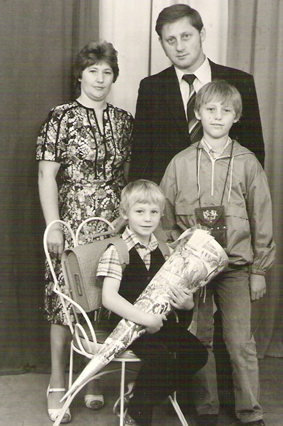 Christian Grothes Familie bei dessen Schuleinführung. Stehend Mutter, Vater, Bruder. Christian auf einem Stuhl sitzend mit einer Zuckertüte in der Hand.
