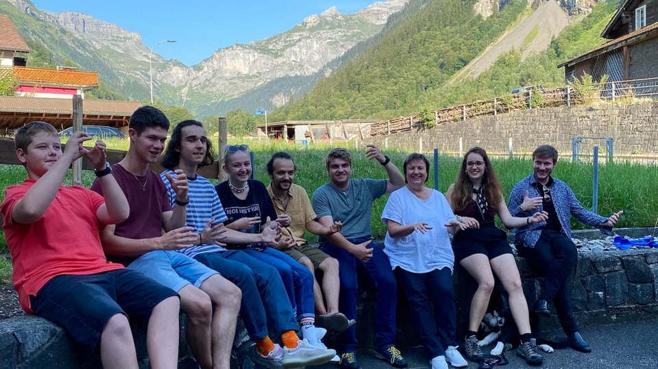 A group of young people, in a world on stone benches outside, mountains behind them.  All replica machines.