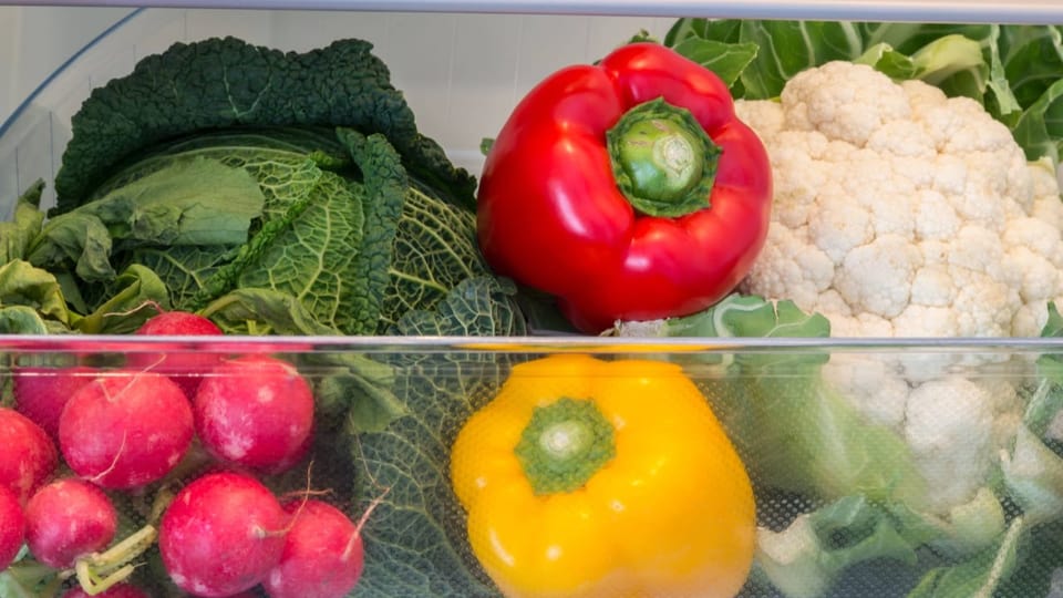 Pepperoni, Blumenkohl und weitere Gemüsearten im Gemüsefach im Kühlschrank.