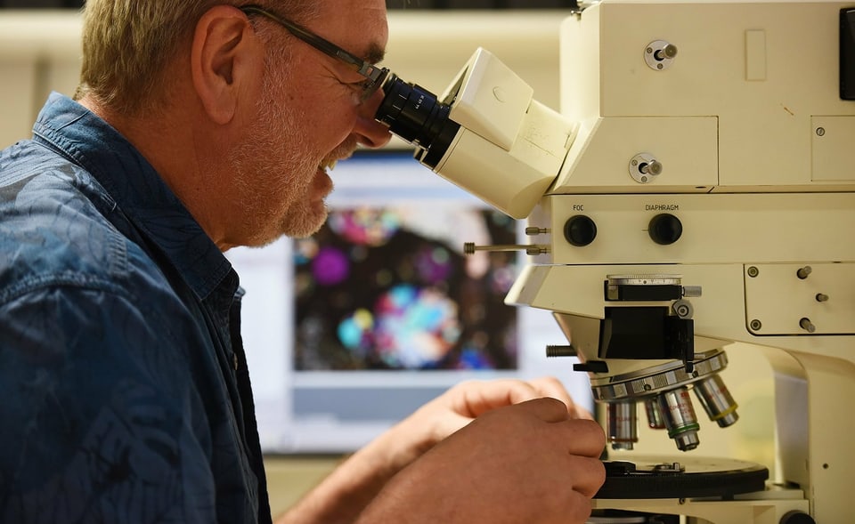 ein Mann untersucht etwas unter dem Mikroskop