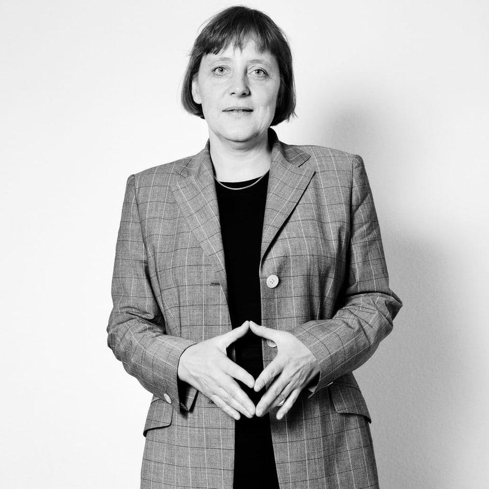 Schwarzweissaufnahme: Frau in Anzug faltet die Hände zur Raute (Angela Merkel)
