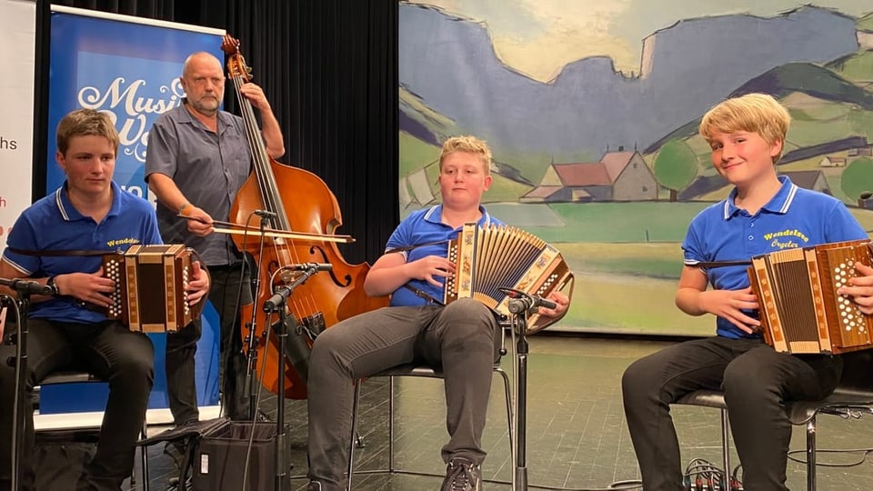 Drei Knaben mit der Handorgel und ein Mann am Kontrabass machen Musik.