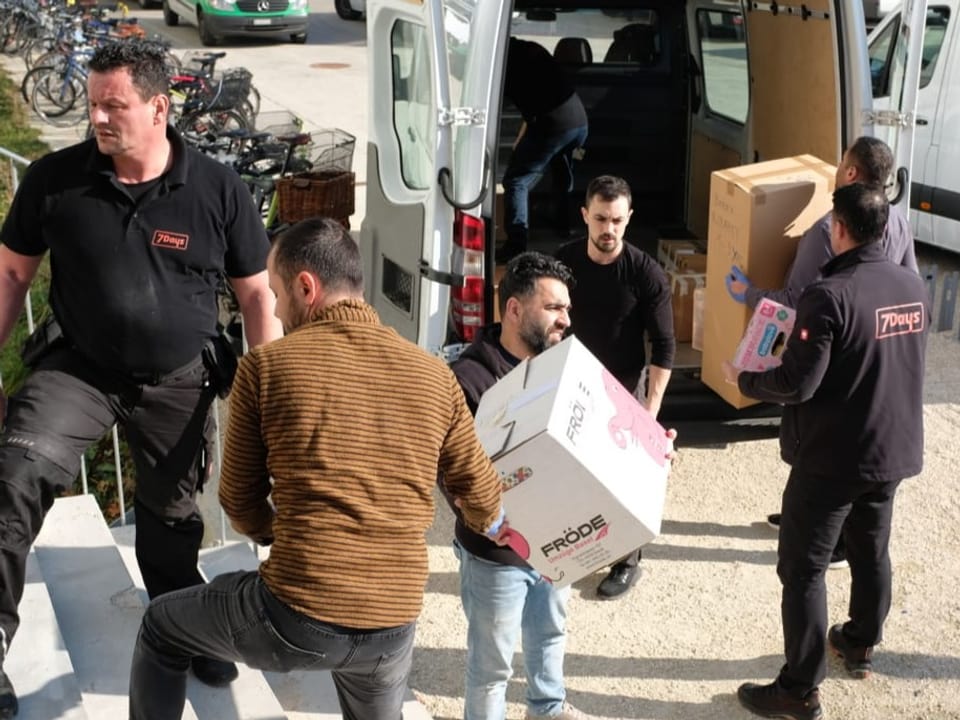 Männer tragen Kartonkisten in einen Lieferwagen.