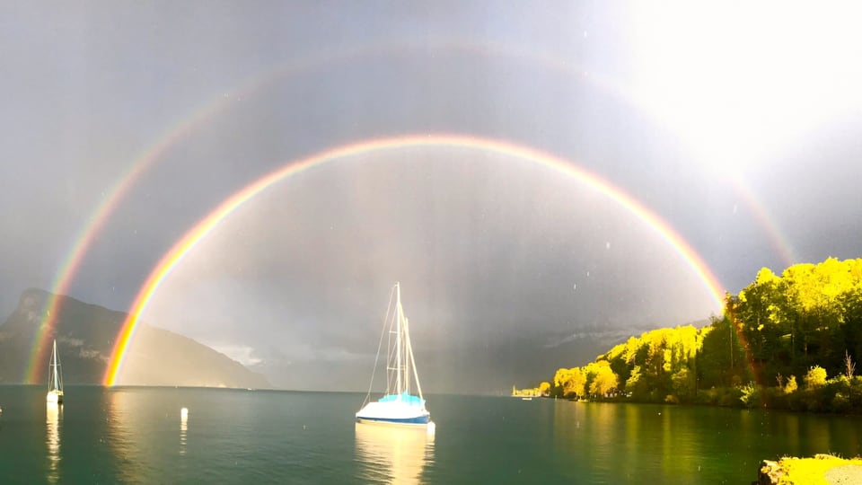 Regenbogen, in der Mitte ein Schiff.