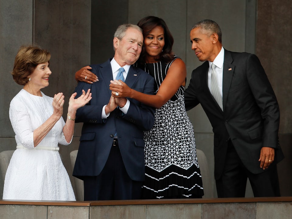 Michelle Obama herzt George W. Bush daneben Laura Bush klatschend und Barack Obama