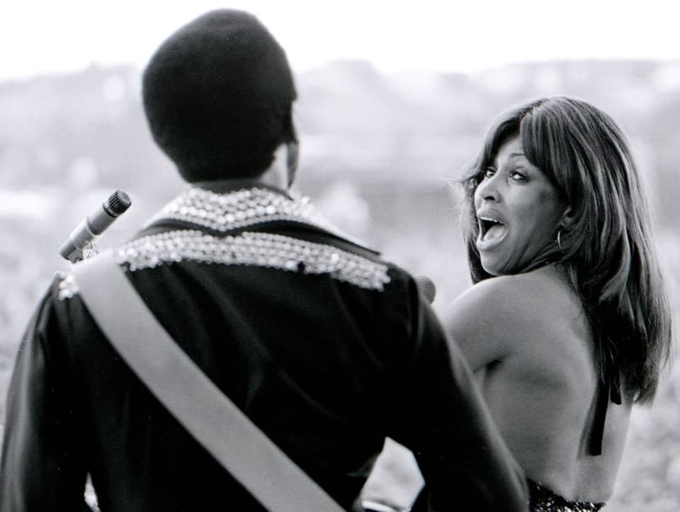 Tina Turner blickt auf Bühne hinter sich zu Ehemann Ike