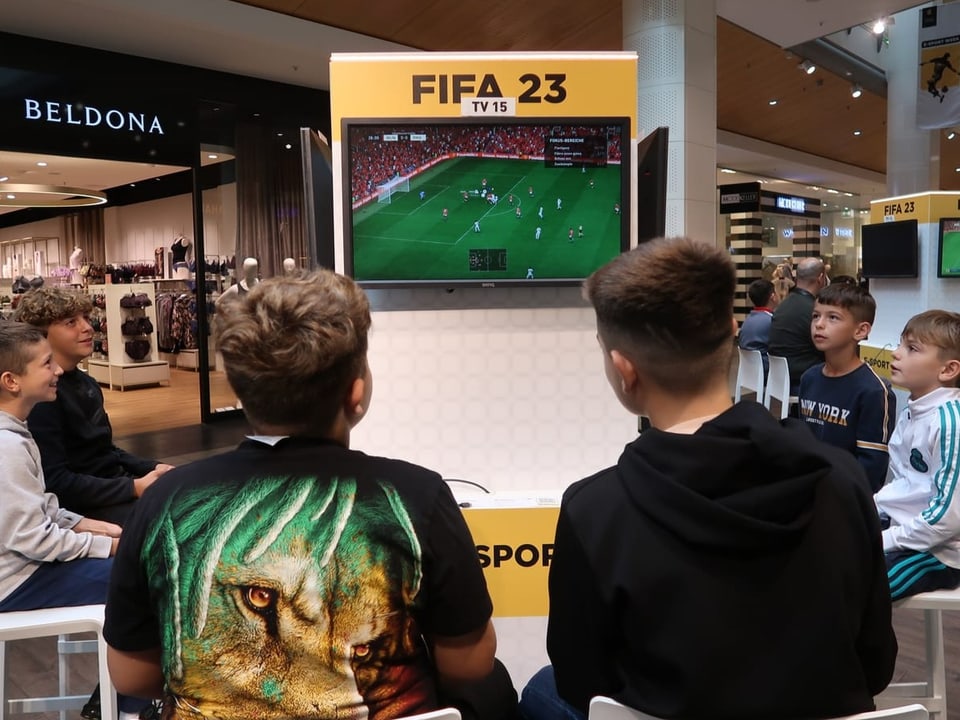 Junge Gamer spielen in einem Shoppingcenter Fifa.