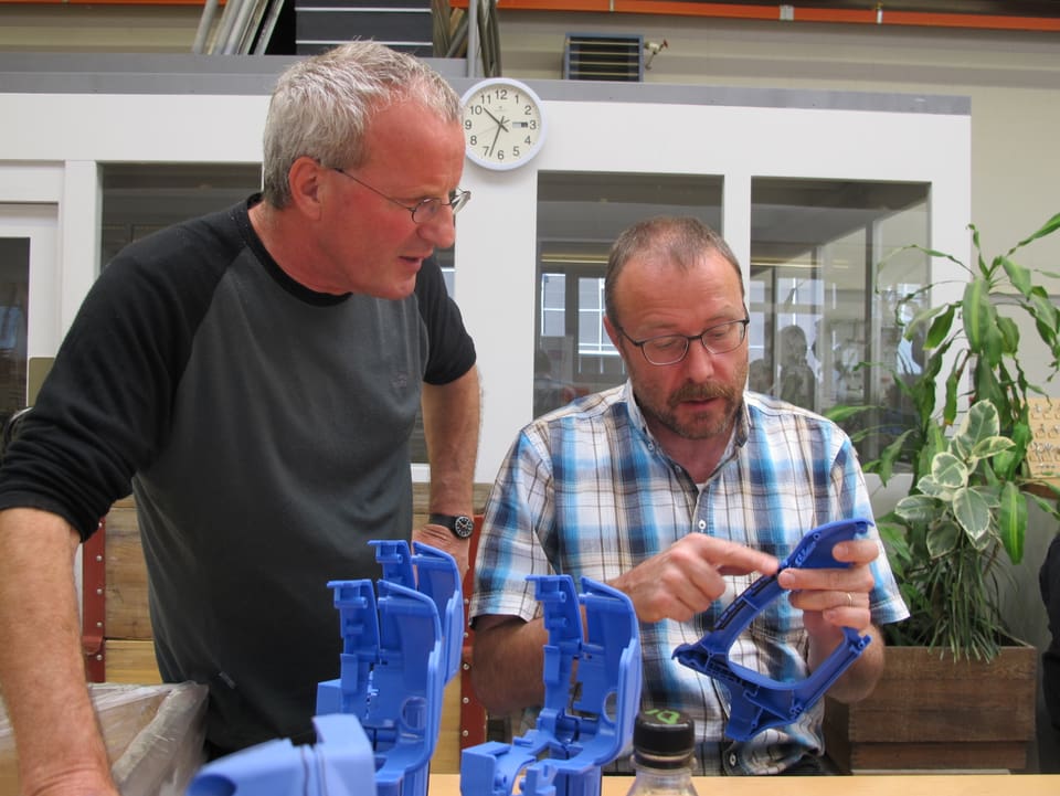 Rindlisbacher sitzt und zeigt einen blauen Plastikgriff der zusammen gesetzt wird.