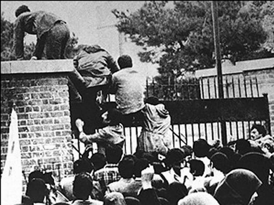 Studenten klettern über das Tor der US-Botschaft in Teheran, im Vordergrund eine Menschenmenge