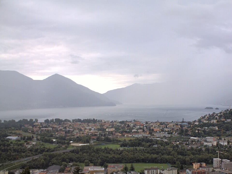 Im Vordergrund ist Locarno zu sehen. Im Hintergrund der Lago Maggiore und ein Regenschleier, der die dahinter liegenden Berge verdeckt.