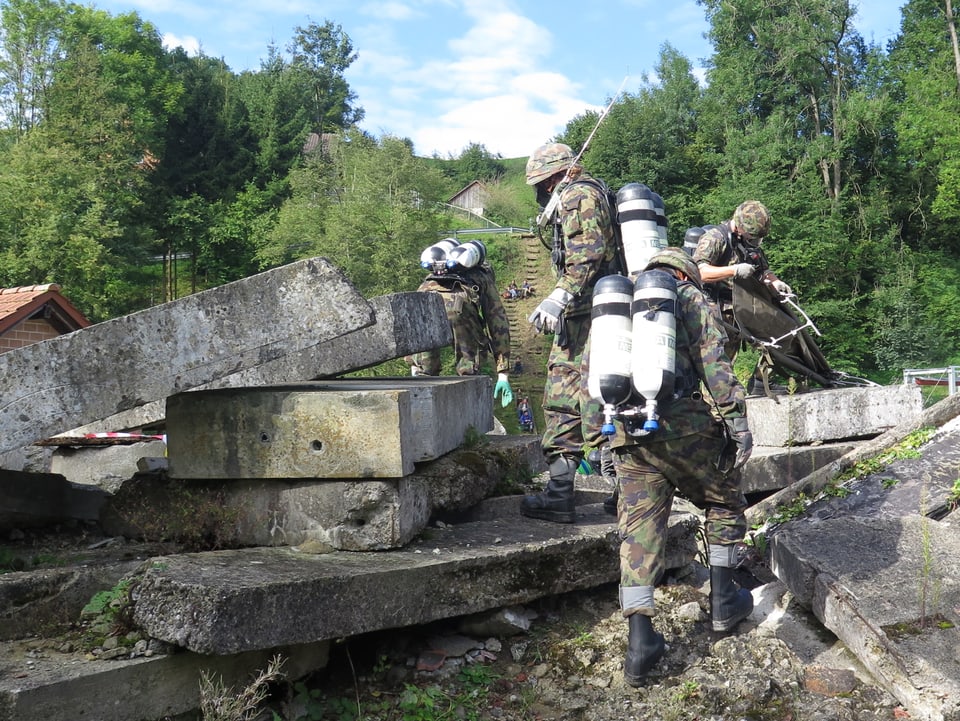 Soldaten miit Sauerstoffflaschen auf dem Rücken bergen Verletzte aus Betontrümmern. 