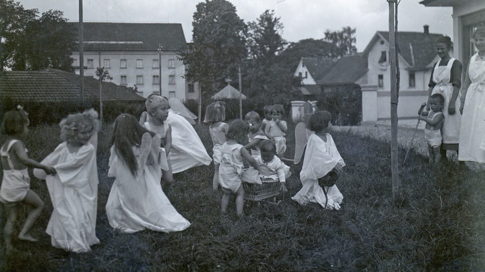 Schwarz-Weiss-Aufnahme aus ca. 1930 mit auf der Wiese spielenden Kindern.
