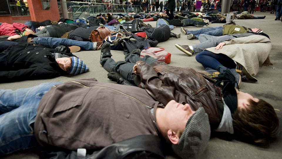 Flashmob: Ein Flashmob im Hauptbahnhof Bern: 50 Personen liegen auf dem Boden.