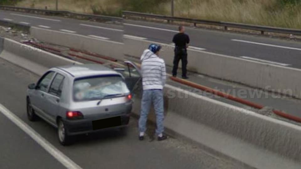 Zwei Männer urinieren auf der Autobahn neben ihrem Auto.