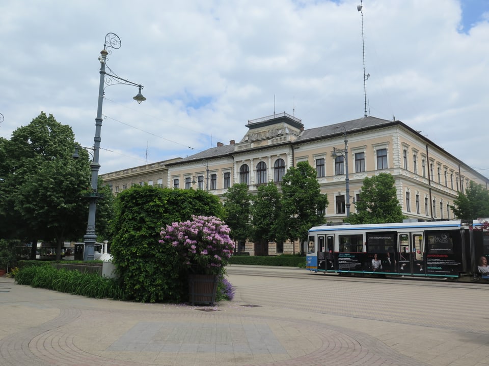 Die historische Innenstadt von Debrecen. Ein Tram fährt vorbei. Die Grünanlagen sind gepflegt.
