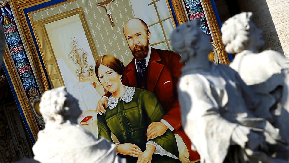 Portrait der Eheleute Louis und Zelie Martin auf einem Wandteppich. der von einem vatikanischen Gebäudebalkon hängt.