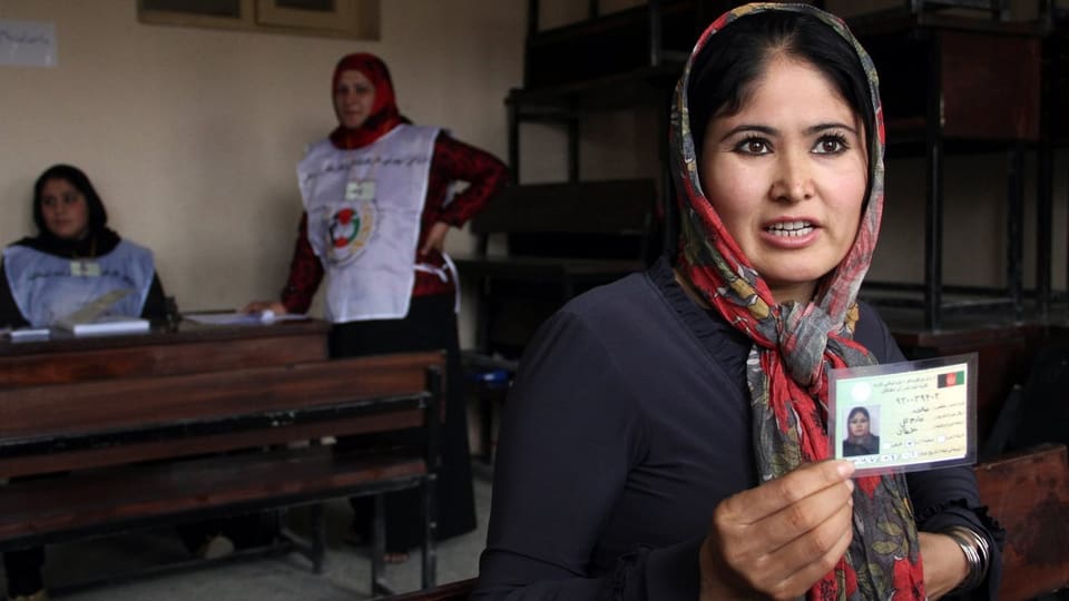 Eine Afghanin präsentiert ihren Wahlrechtsausweis, der in einer Wähler-Anlaufstelle ausgestellt wurde.