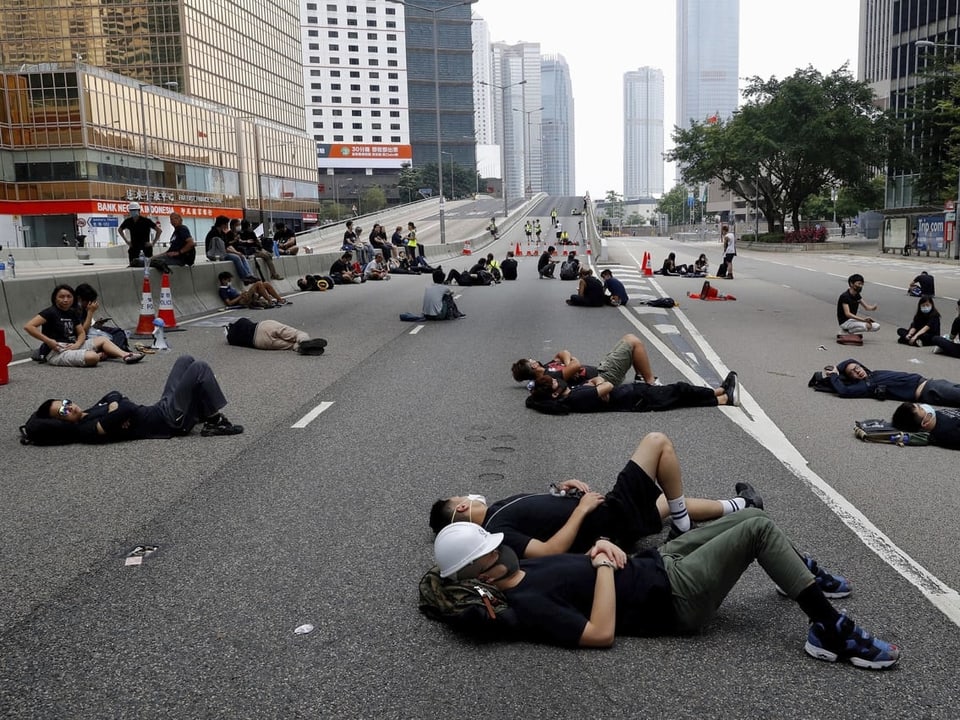 Menschen liegen auf einer Schnellstrasse, um den Verkehr zu blockieren.