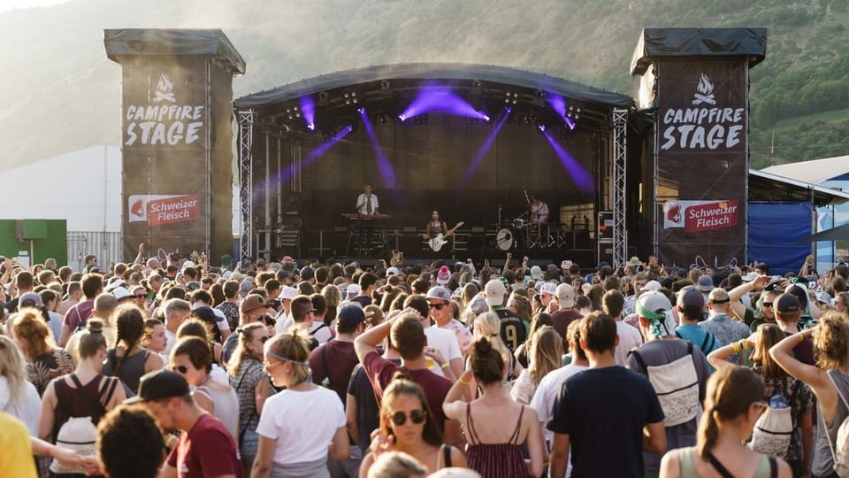 Eine Menschenmenge steht und tanzt vor der Bühne am Gampel-Openair.