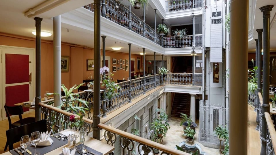 Innenhof eines Hotels. Ringsum Balkone mit gedeckten Tischen.