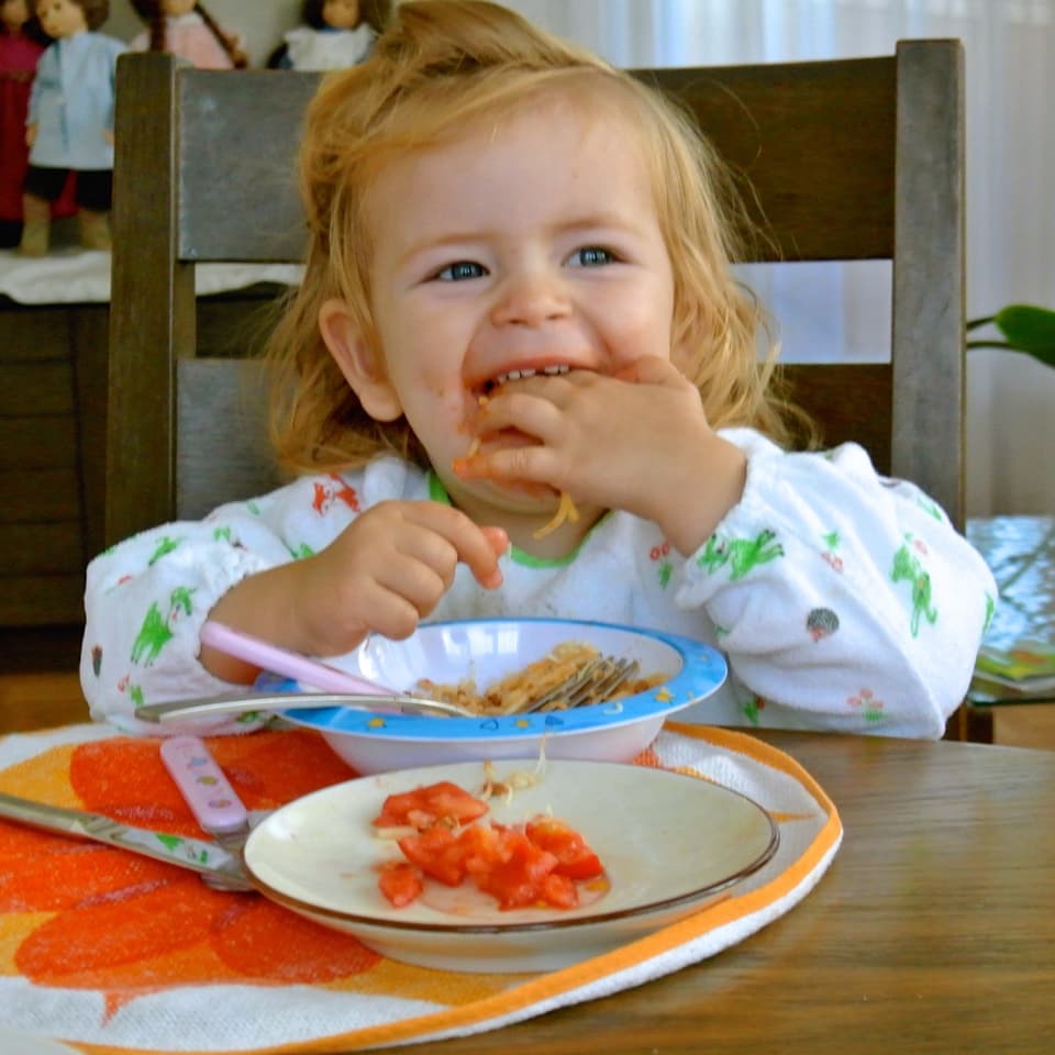 Ein Kleinkind isst Spaghetti.