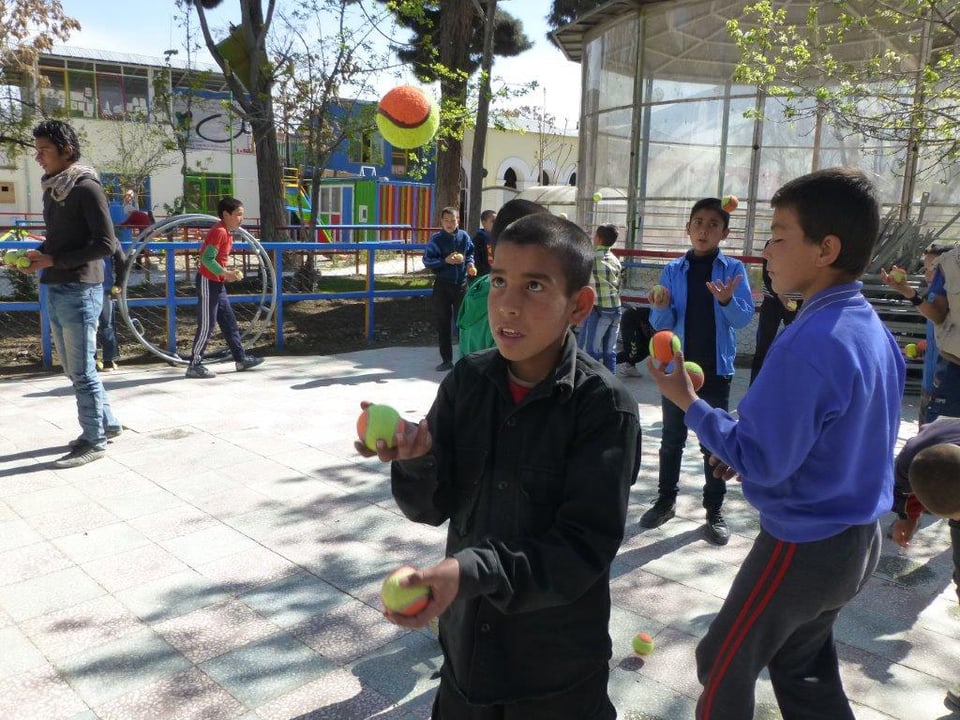 Ein Junge jongliert mit Bällen. 